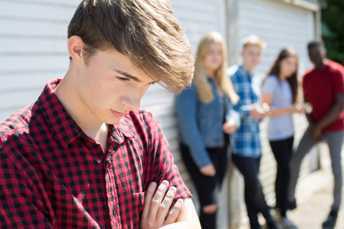 Unhappy Teenage Boy Being Gossiped About By Peers